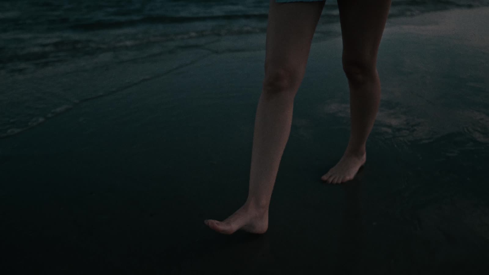 Bare feet on dark sand at dusk
